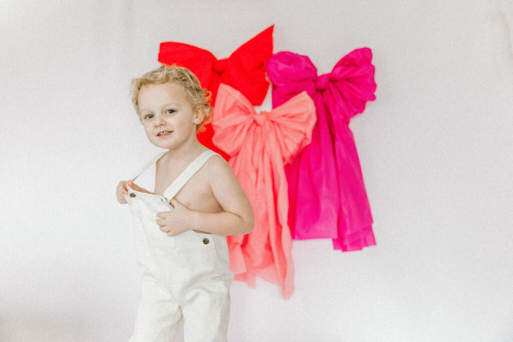 toddler taking photos in front of giant pink bows