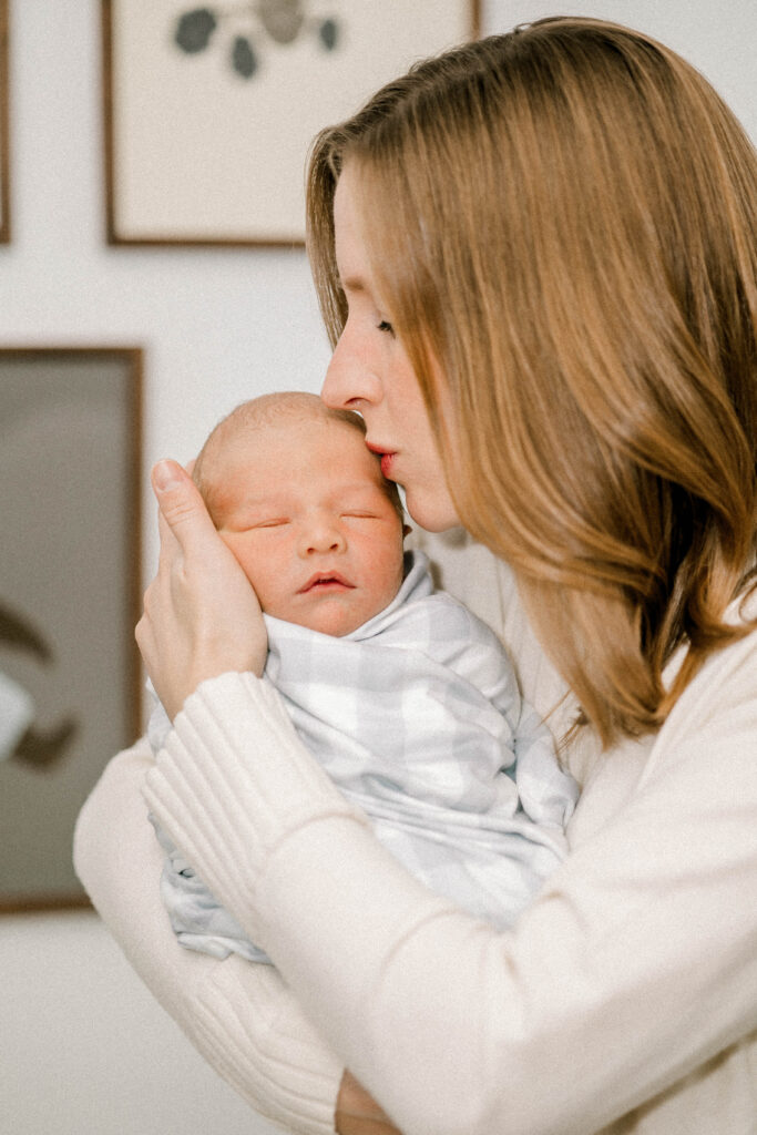 Newborn baby Boy wrapped in gingam print swaddle held by his mother