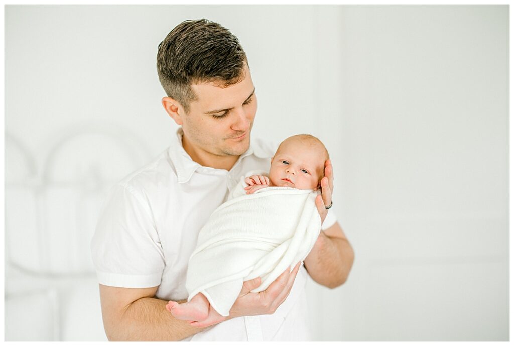 Dad holding newborn son during studio photography session in Indianapolis