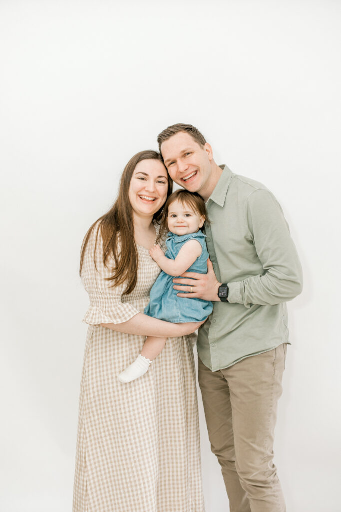 Family of three celebrating baby’s first birthday with studio portraits