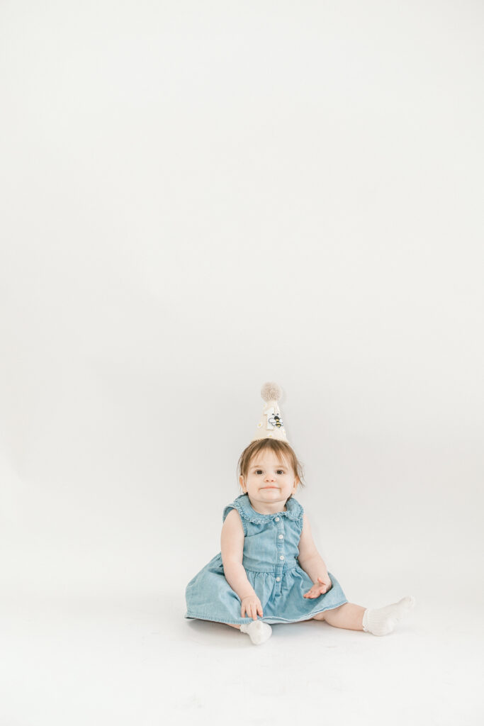 One year old baby Darcy sitting and smiling during studio milestone session