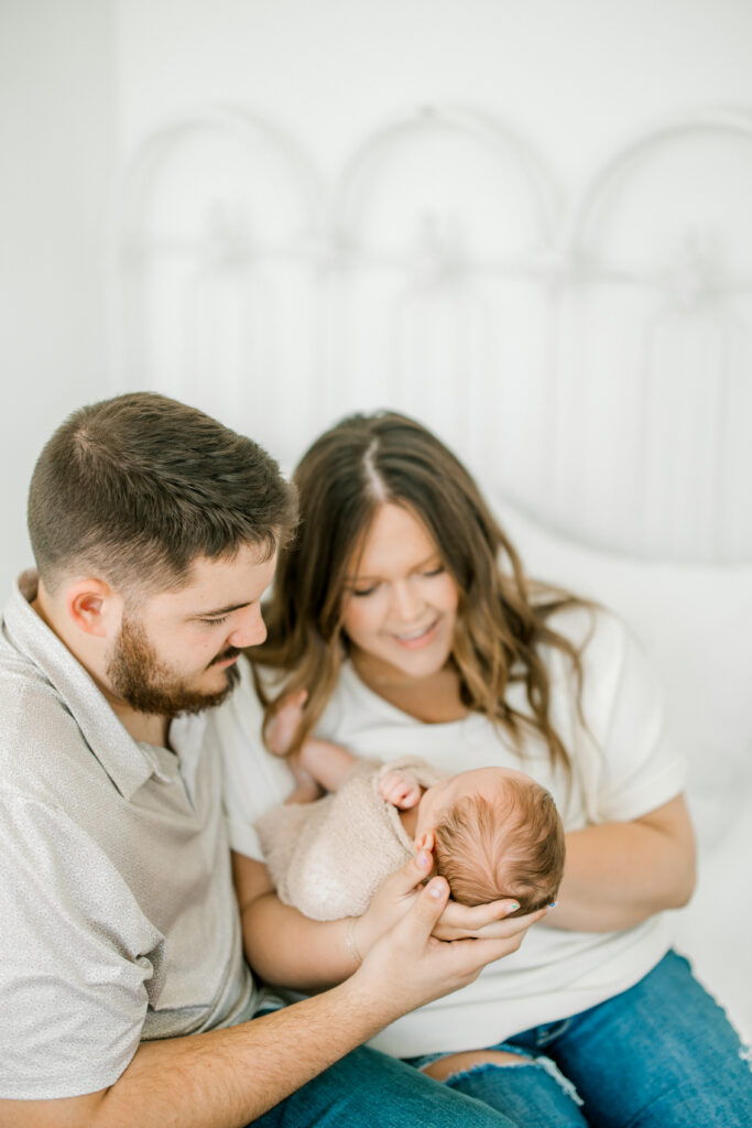 Candid moment of parents cuddling Baby Beau during newborn photography session